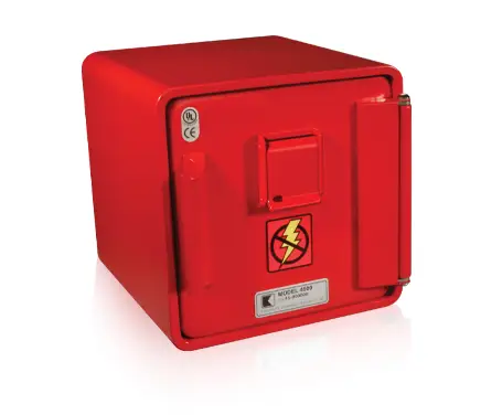 A red metal box with a front door featuring a handle, a small flap, and a caution symbol for electrical hazards. The box has certification labels and reflective surface underneath, indicating it may be used for housing electrical components.