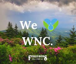 A scenic view of lush green mountains with colorful flowers in the foreground under a cloudy sky. The text "We ♥︎ WNC." is prominent, with "Ferguson's Well & Pump SVC" at the bottom.
